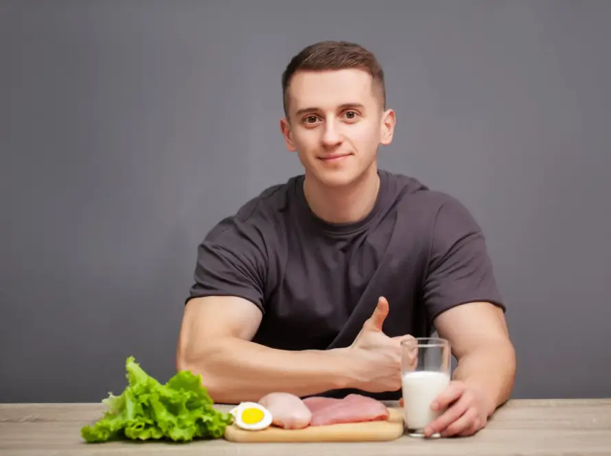 Person smiling and looking at a variety of healthy foods like avocado, nuts, and seeds on a table