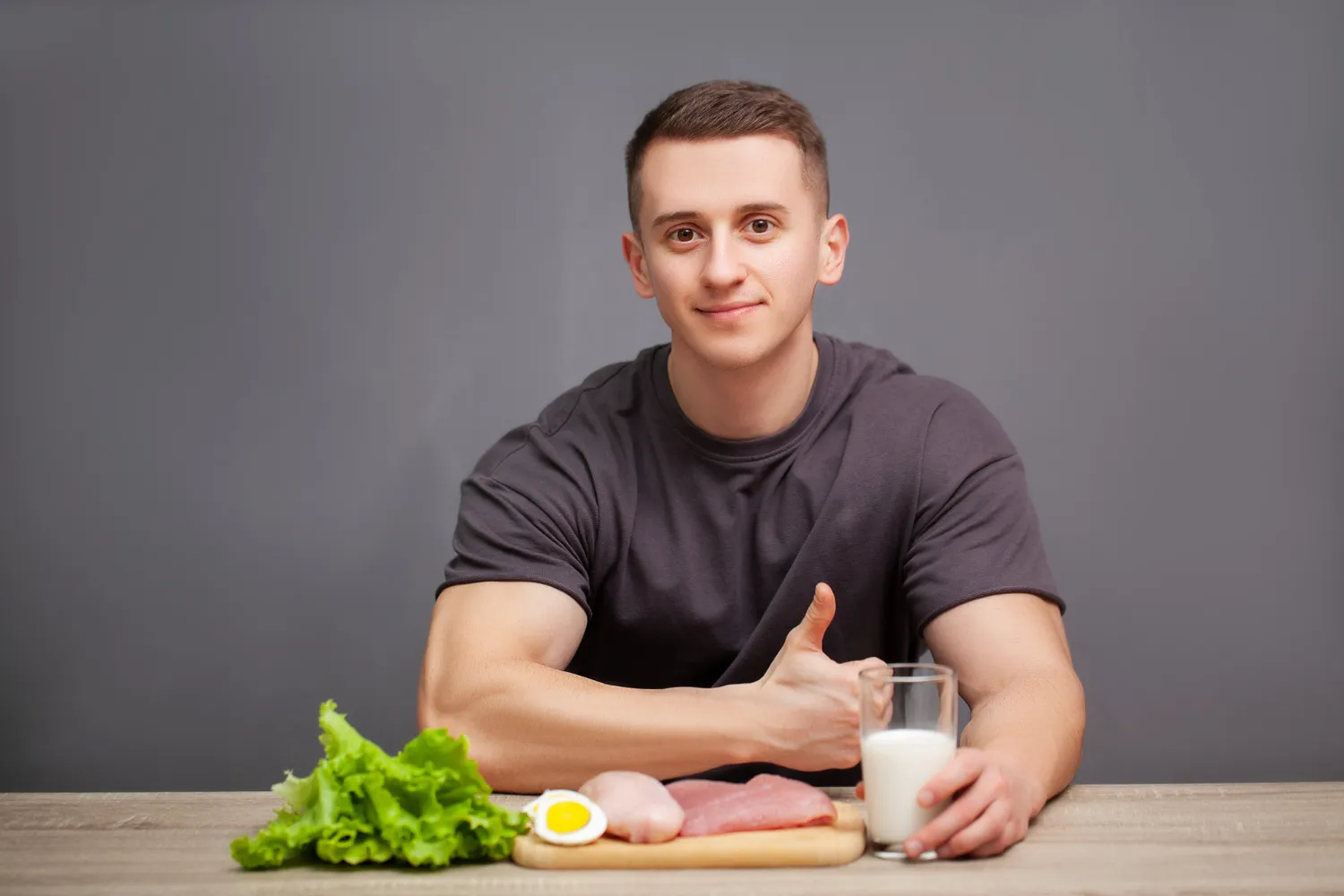 Person smiling and looking at a variety of healthy foods like avocado, nuts, and seeds on a table
